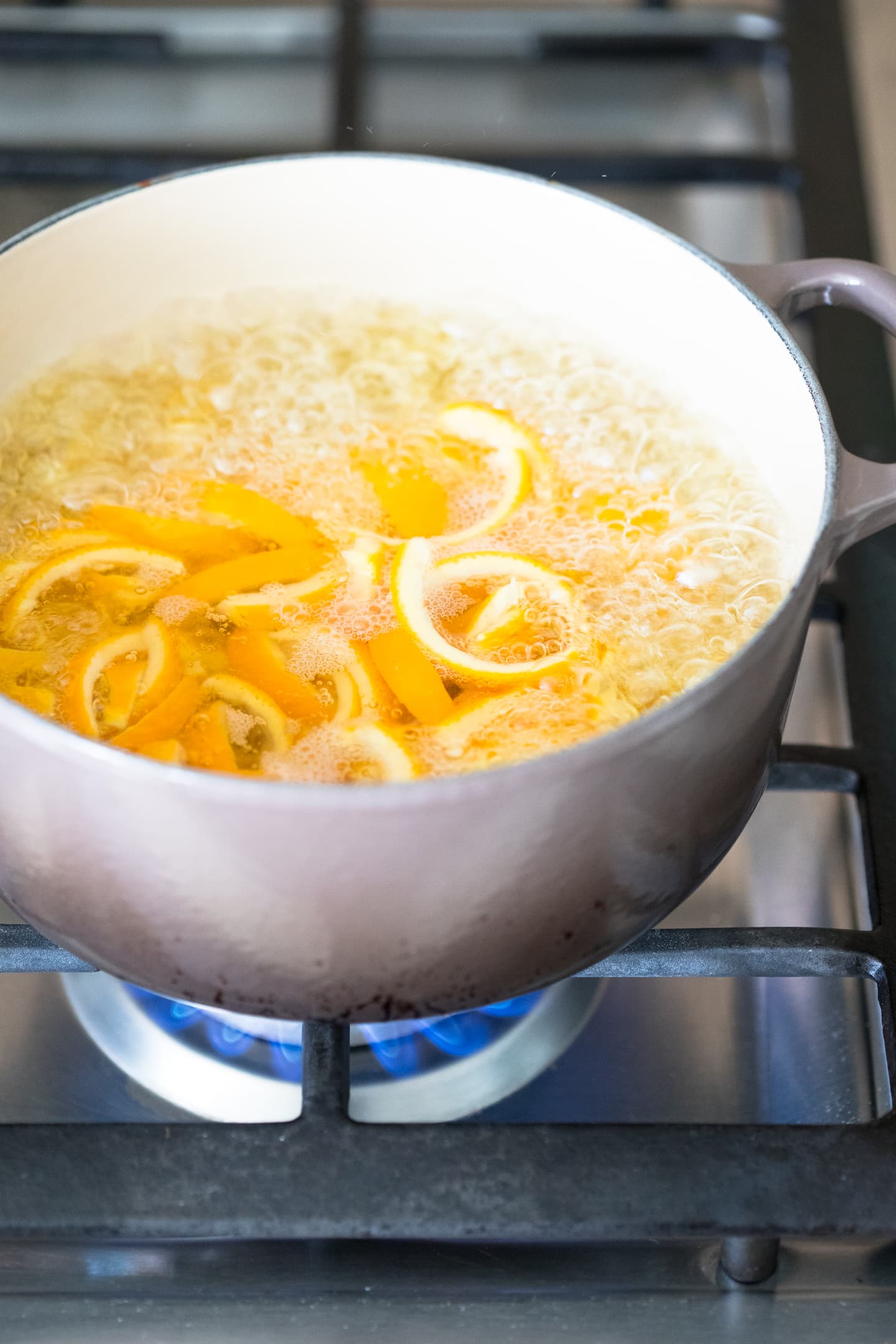 Angled view of orange peels being balanced in a pot on the stove.