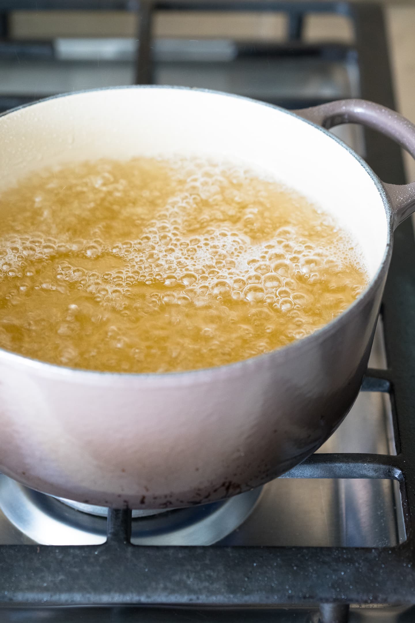 Angled view of sugar syrup simmering in a pot on the stove.