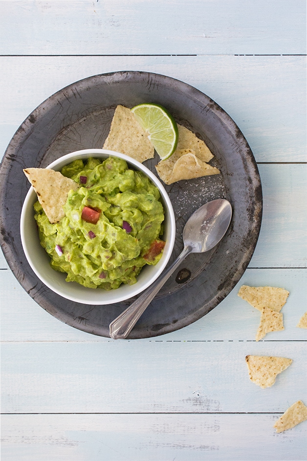 A recipe for fresh, spicy guacamole loaded with red onion, tomato, and a touch of lime juice for maximum flavor. Takes minutes to make and SO much better than store-bought! | www.brighteyedbaker.com