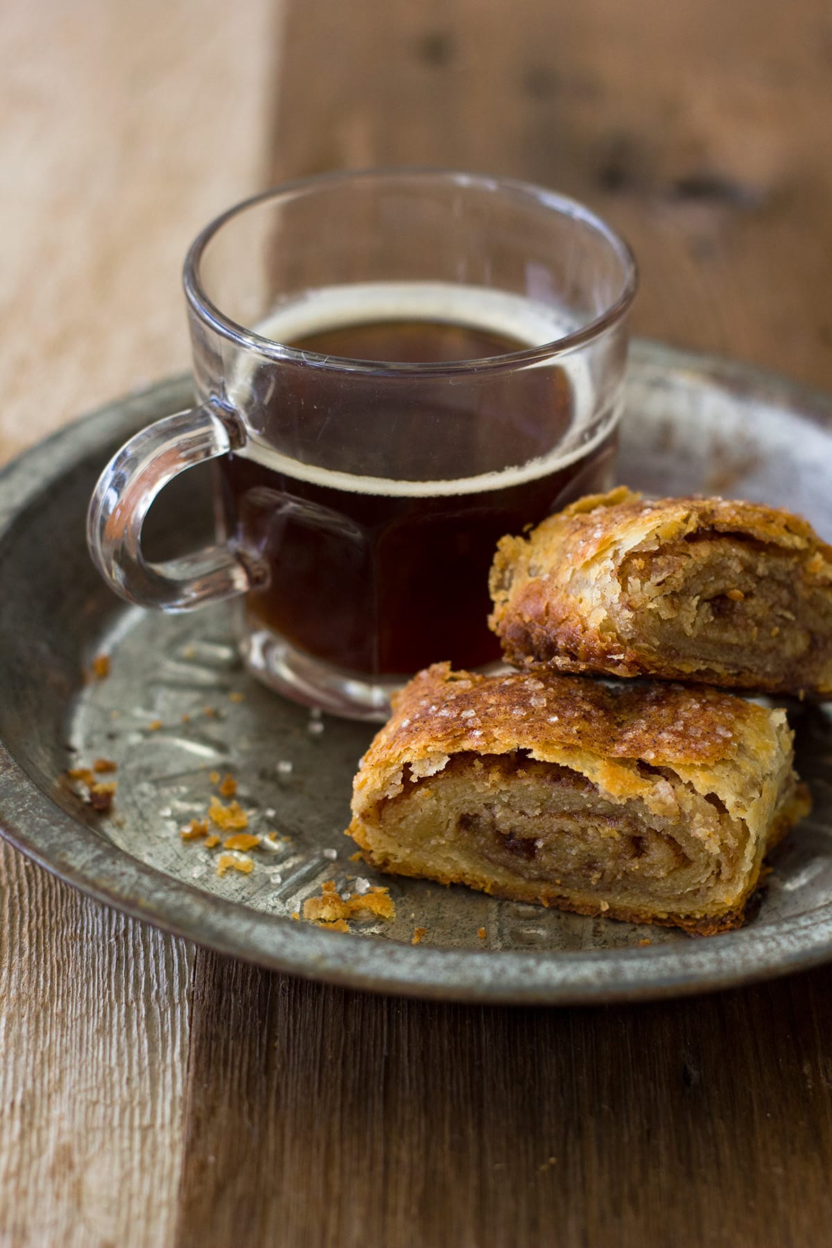 Two cinnamon sugar pastries on a metal pie plate with a cup of coffee.