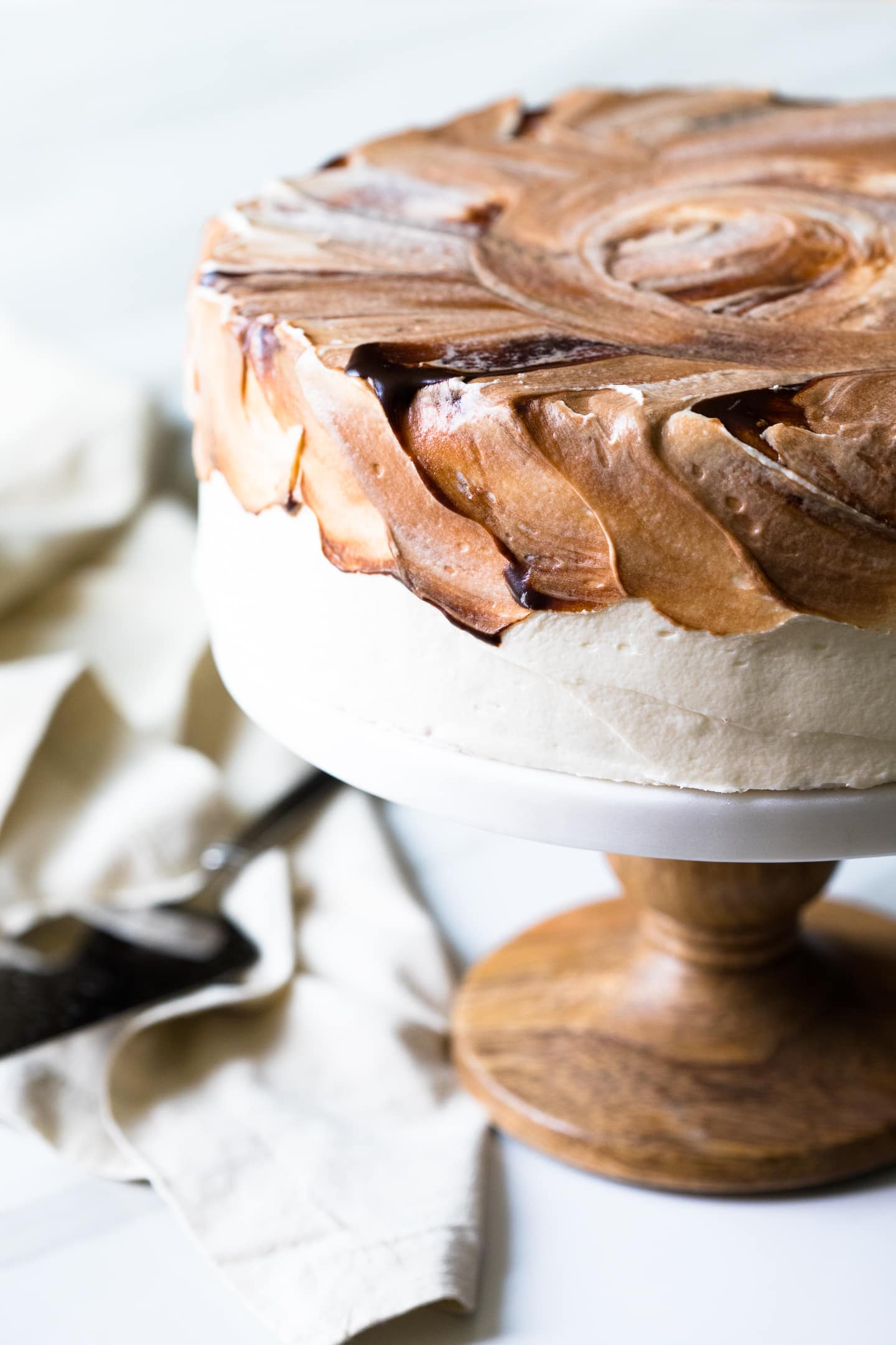 Front-angled view of Vietnamese Coffee Cake with a chocolate-swirled Sweetened Condensed Milk Frosting, sitting on a wooden cake stand