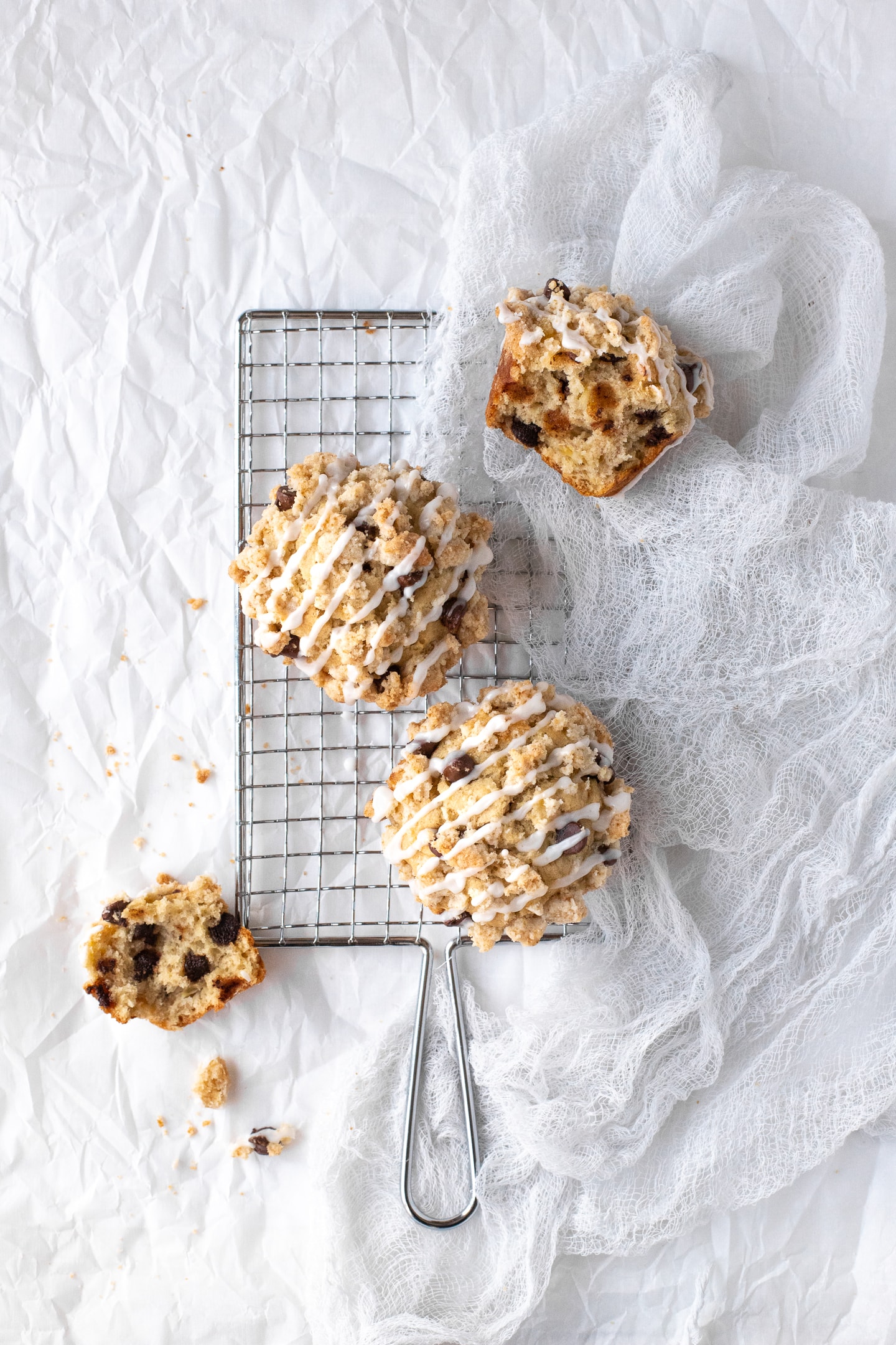 Overhead view of two whole muffins on top of a safety grater, with portions of a muffin scatter around the sides, over a white backdrop.
