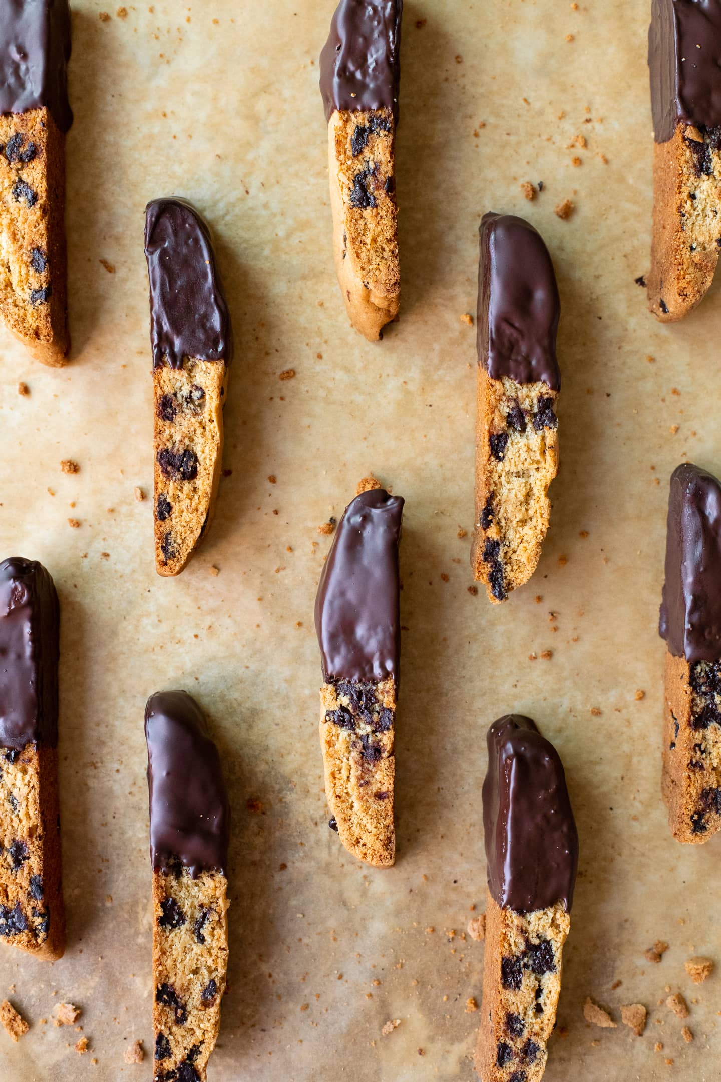 Chocolate chip biscotti dipped in chocolate and arranged on a baking sheet.