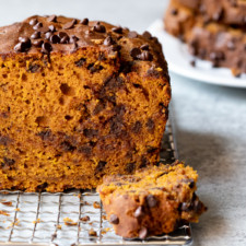 Front-facing view of center cut of pumpkin bread, with slices stacked on a plate in the background.