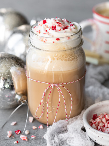 Mocha topped with whipped cream, with peppermint candy and ornaments in the background.