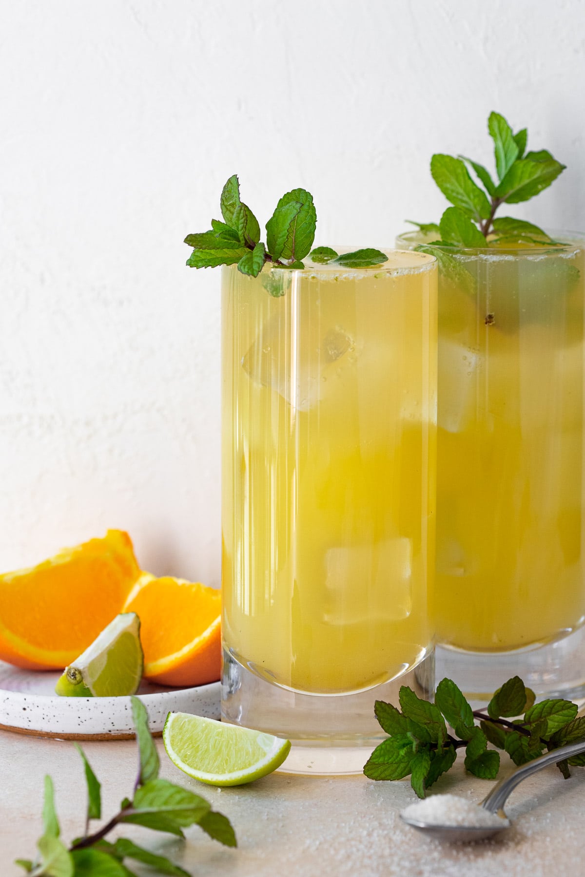 Two orange mojitos served in highball glasses, garnished with fresh mint sprigs.