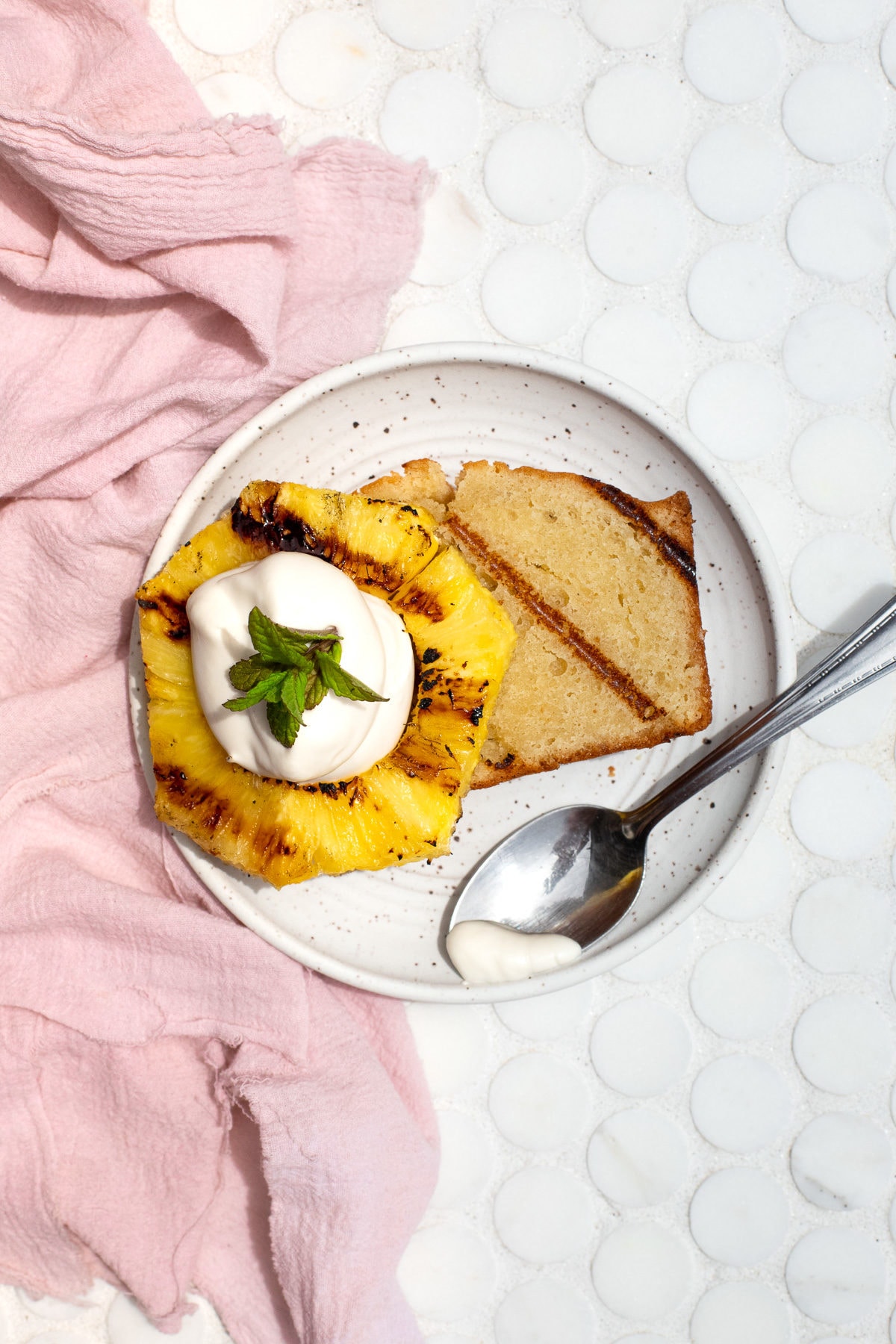 Overhead view of a slice of grilled pound cake topped with grilled pineapple and whipped cream.