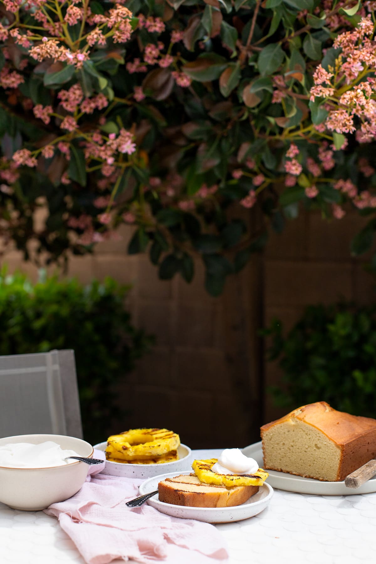 Pound cake being served with pineapple slices and whipped cream on a patio table.