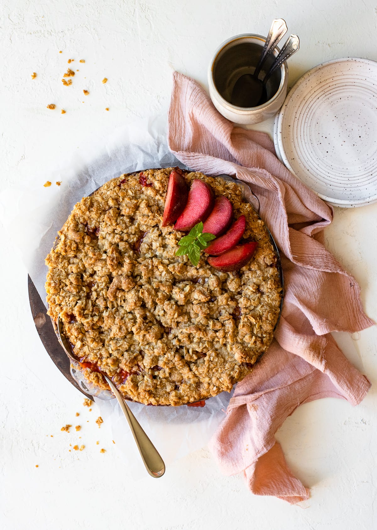 Fruit crumble baked in a pie dish, topped with plumogranite slices and a mint garnish.