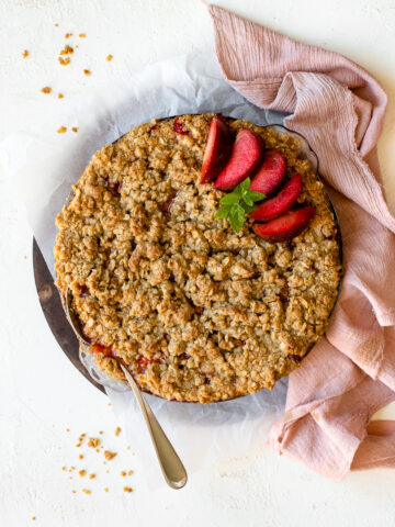 Fruit crumble baked in a pie dish, topped with plumogranite slices and a mint garnish.