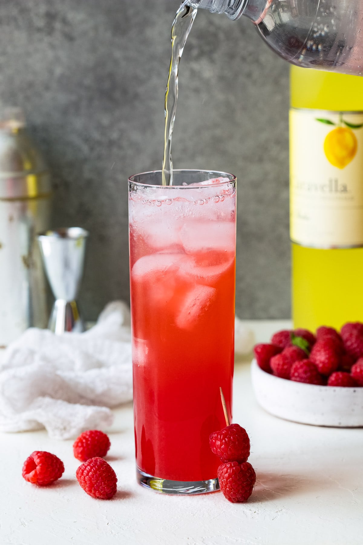 Club soda being poured into a raspberry limoncello cocktail.