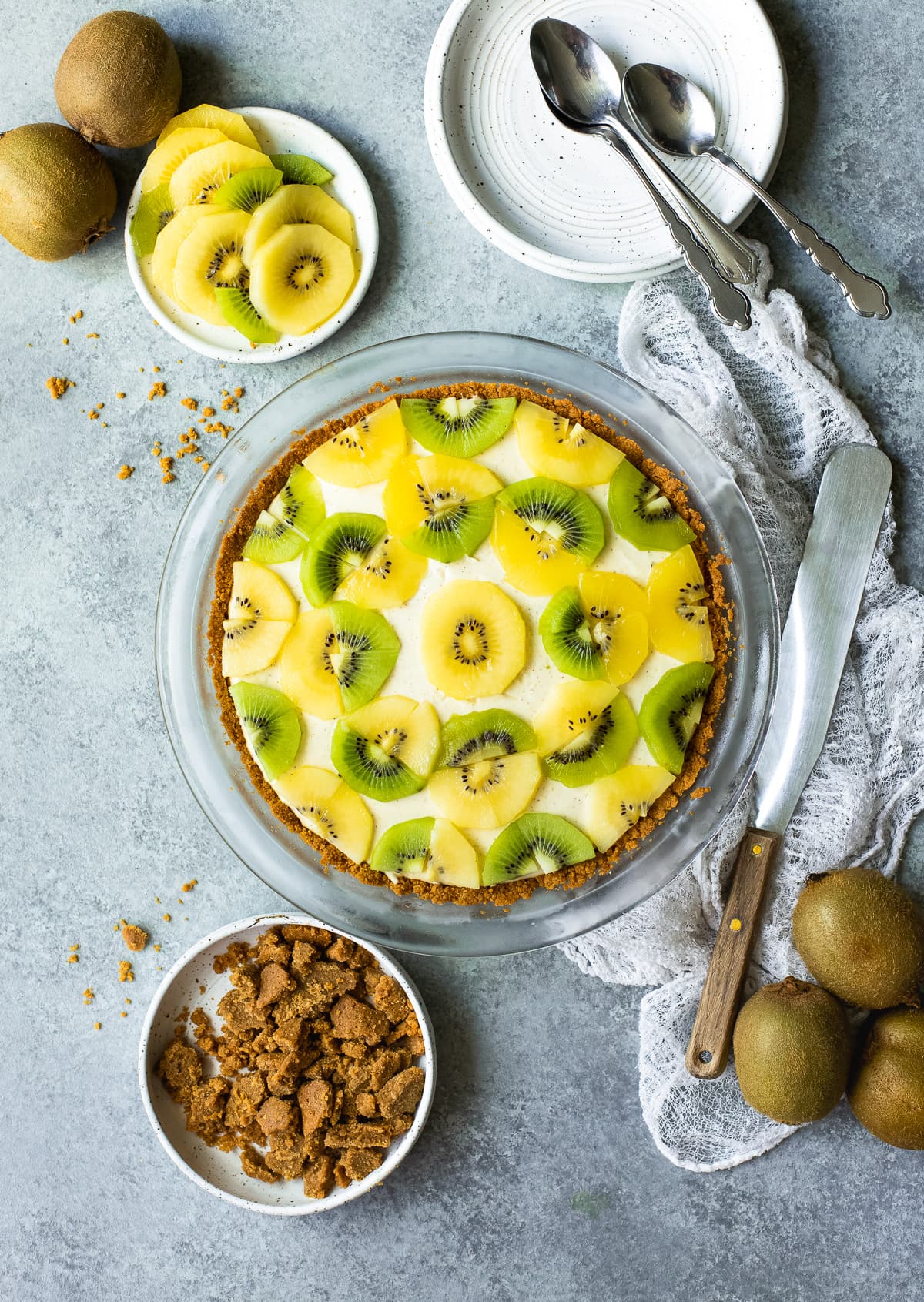 Kiwi lime pie surrounded by graham cracker crumbs and fresh kiwi.