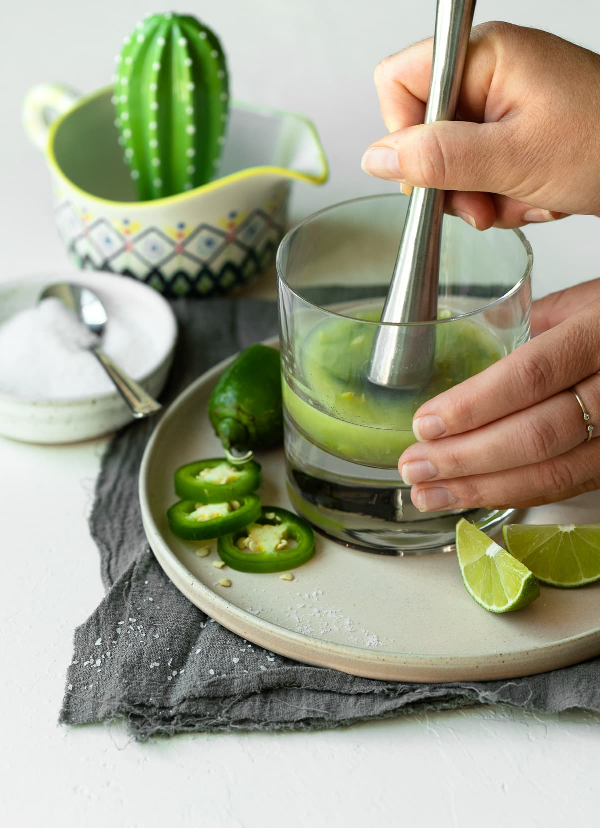 Lime and jalapeno slices being muddled together.