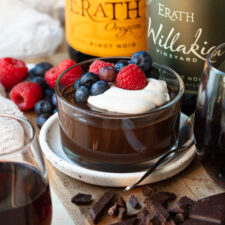 Small ramekin filled with chocolate pudding and topped with berries and whipped cream.