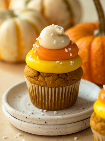 Cupcake on two stacked plates with frosting colored to look like candy corn.