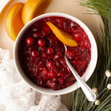 Bowl of homemade cranberry sauce garnished with an orange peel.