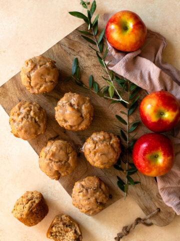 Glazed muffins with kanzi apples on a wooden board.