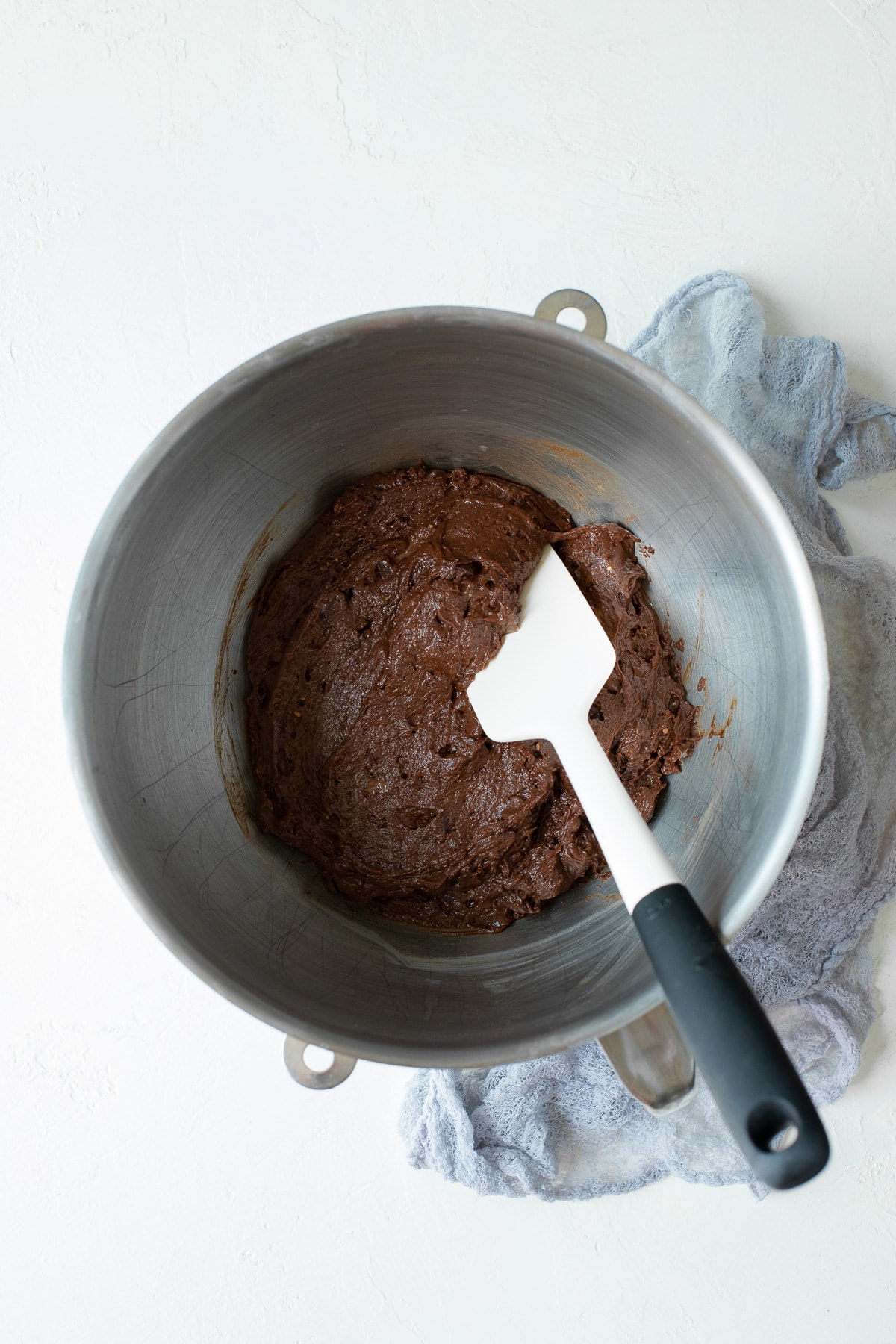 Chocolate muffin batter being mixed with a spatula in a bowl.