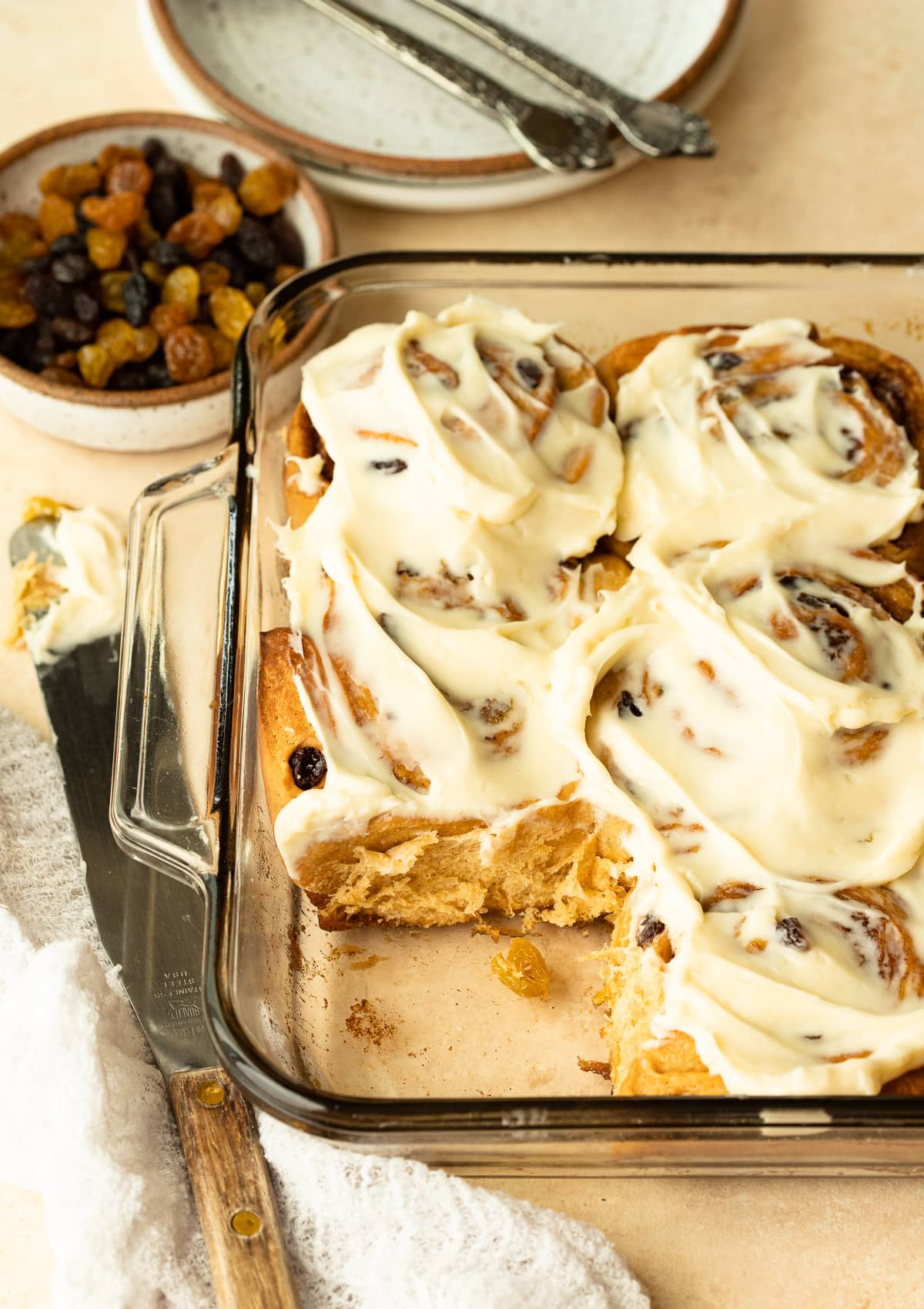 Homemade cinnamon rolls in a glass dish topped with frosting.