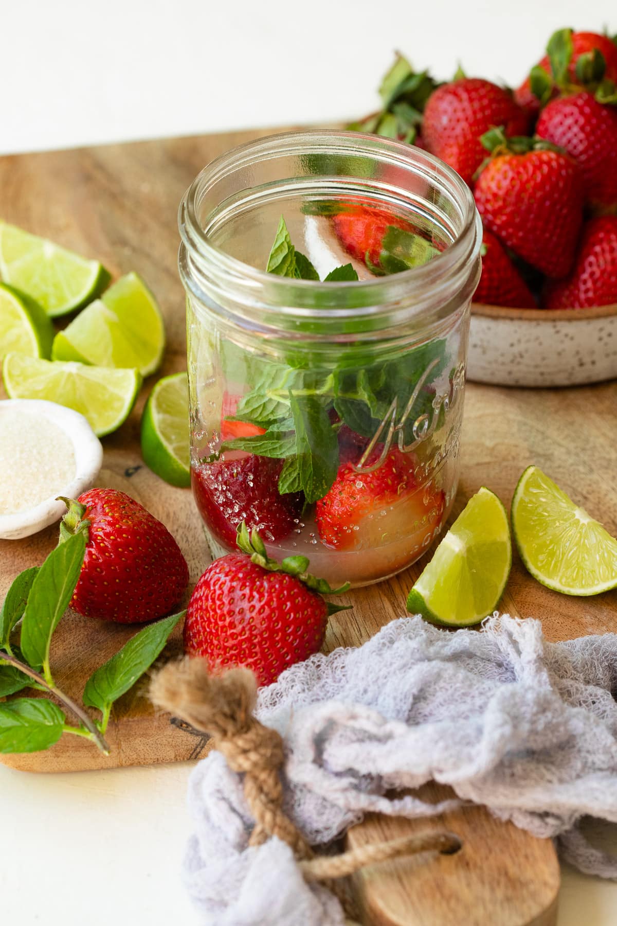 Strawberries, mint, and lime juice in a mason jar.