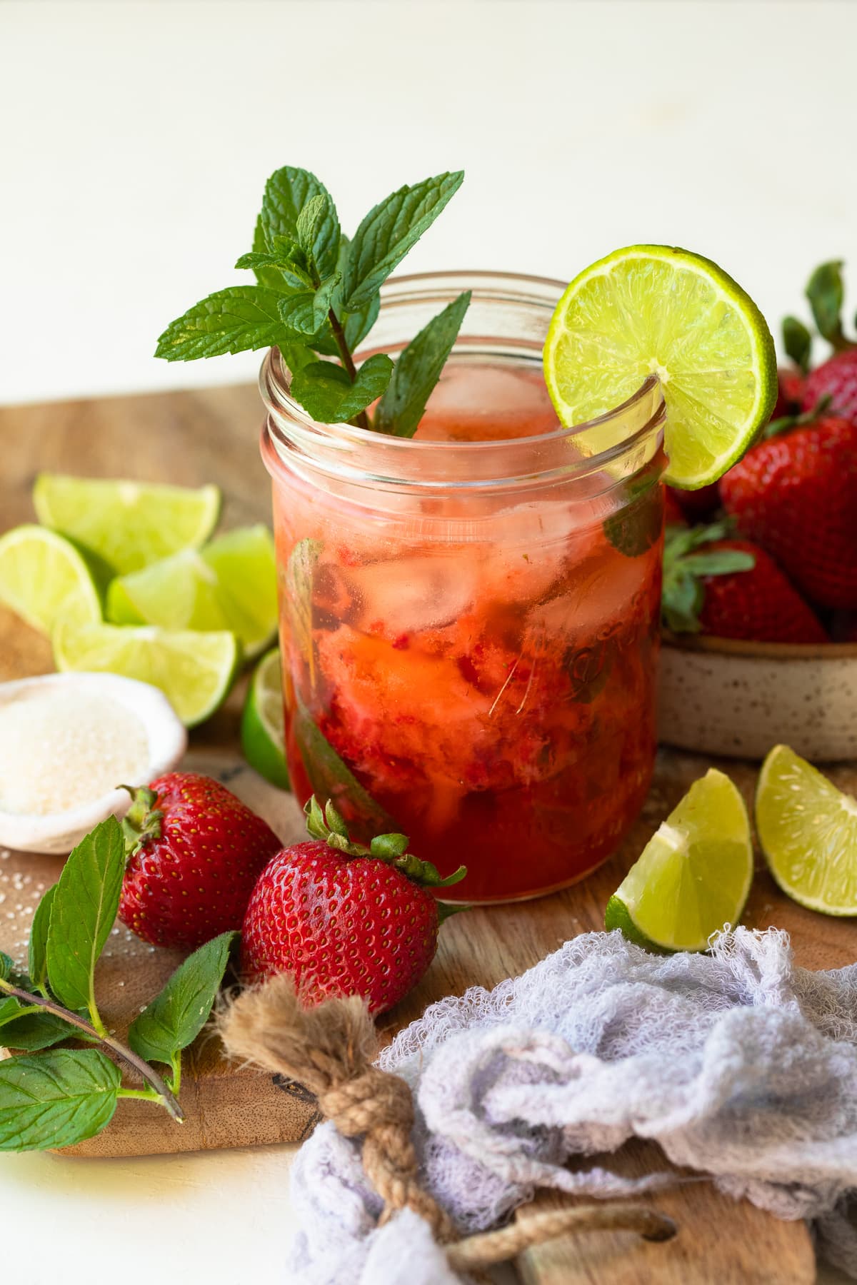 A mojito in a mason jar garnished with lime and mint, surrounded by recipe ingredients.