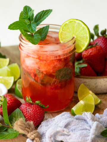 A mojito in a mason jar garnished with lime and mint, surrounded by recipe ingredients.
