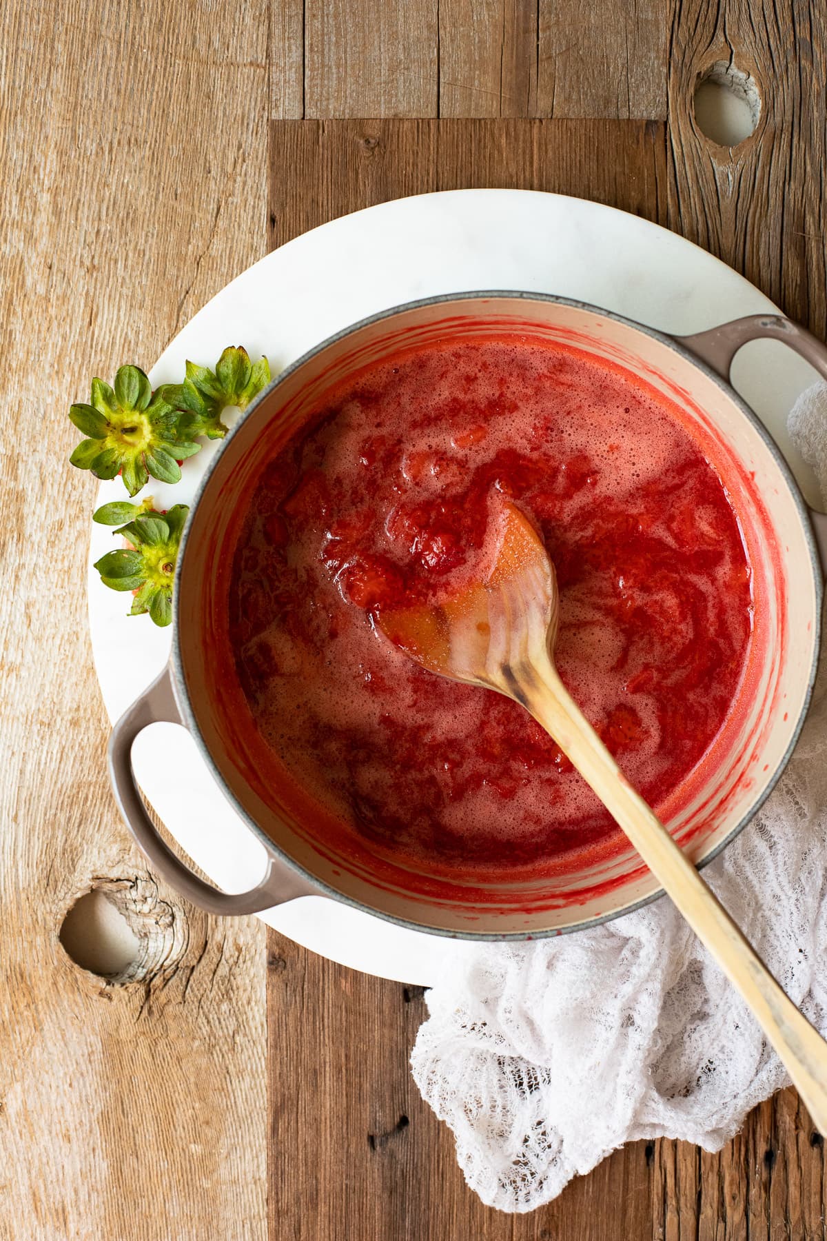 Strawberries simmered with sugar in a saucepan.