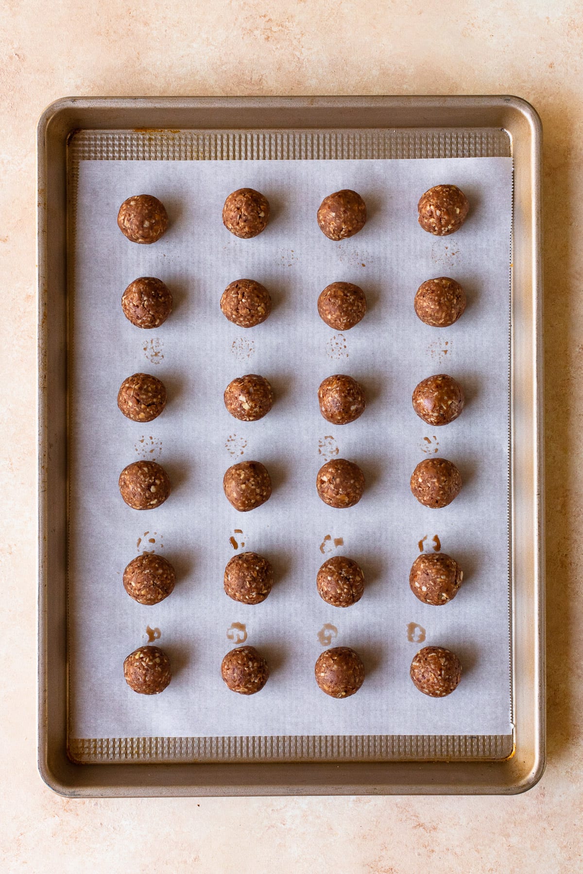 Cookie dough rolled into balls on a parchment-lined cookie sheet.
