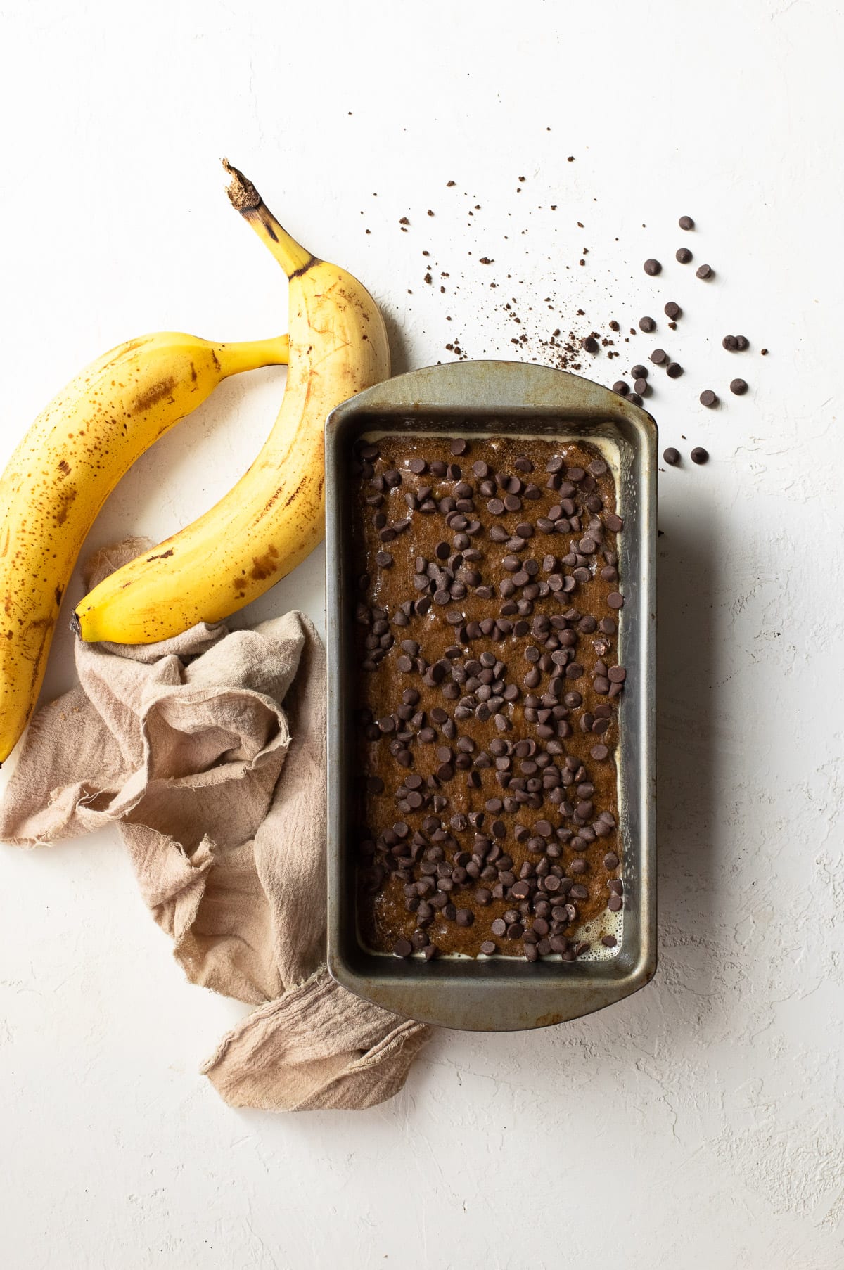 Banana bread batter in a loaf pan topped with mini chocolate chips.