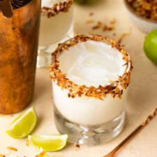Two coconut margaritas with lime wedges.