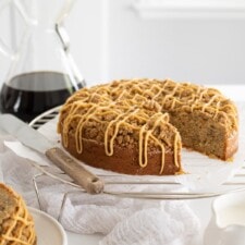 Coffee cake with a slice on a plate, served with coffee.