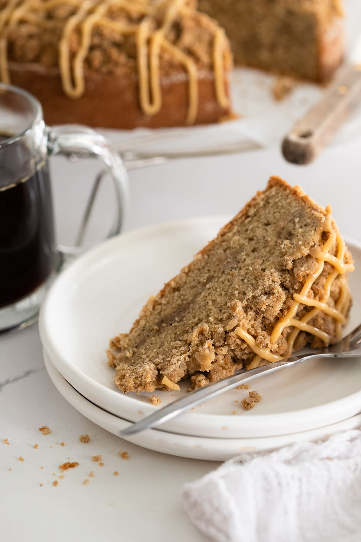 A slice of coffee cake on a plate, served with coffee.