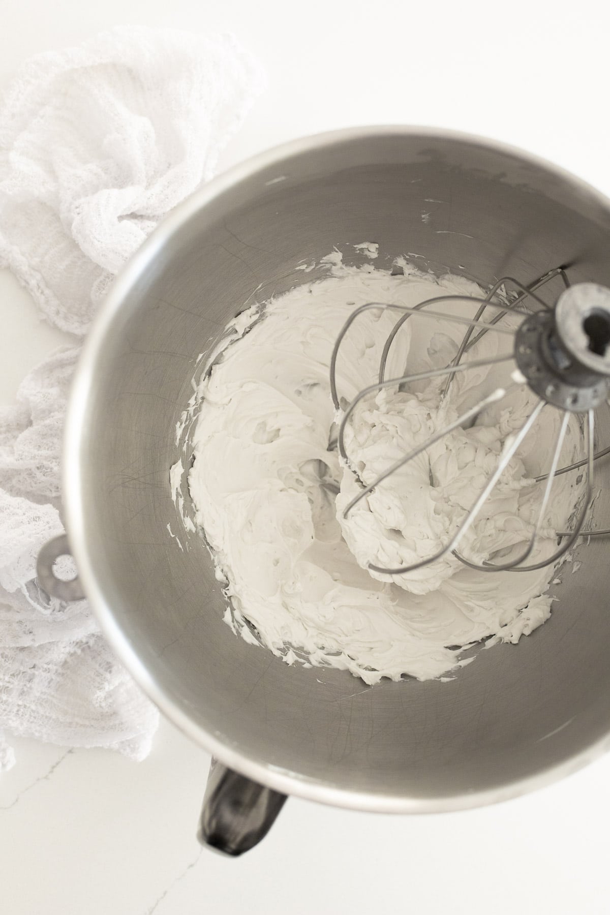 Whipped coconut cream in the bowl of a stand mixer.