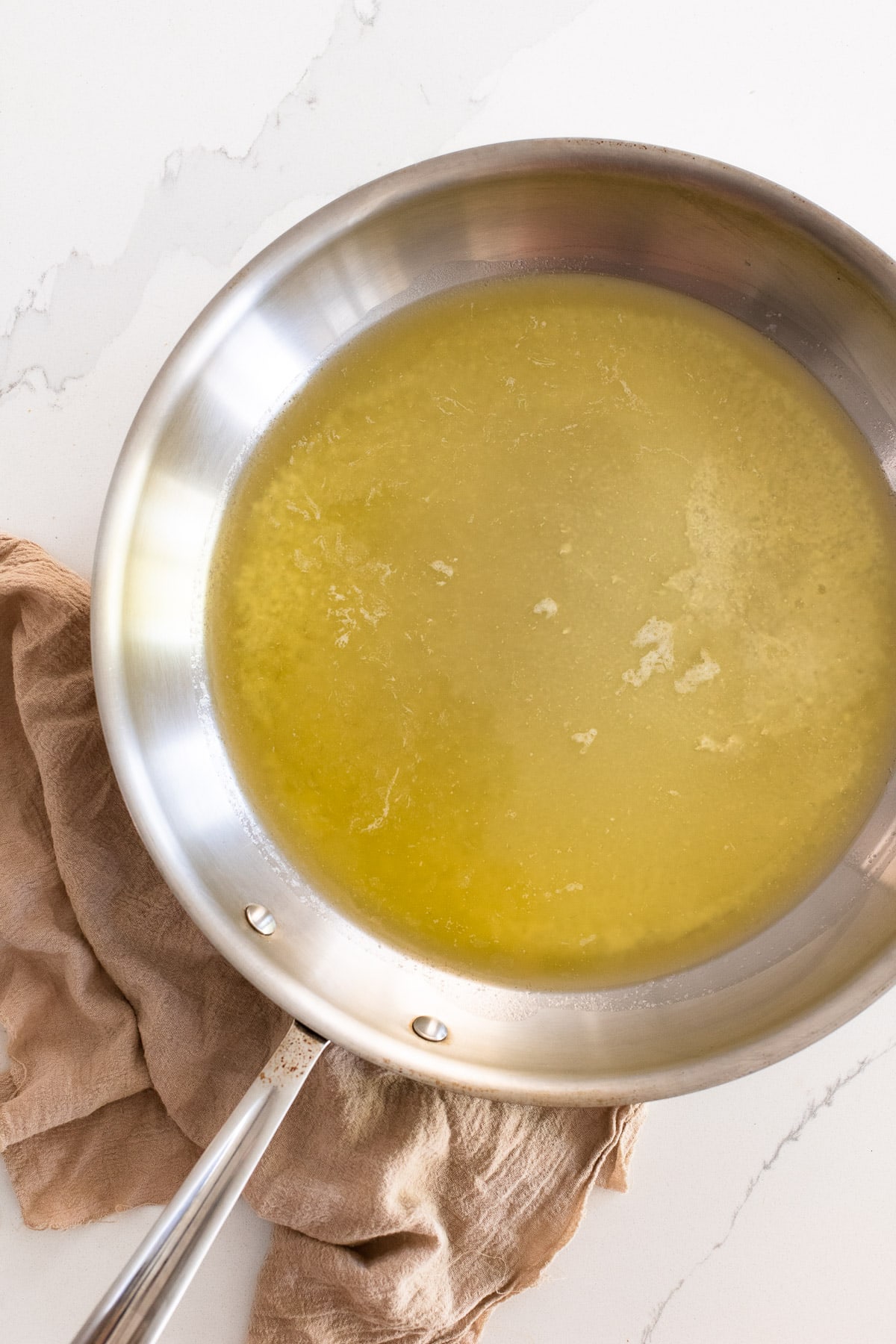 Melted butter in a stainless steel frying pan.