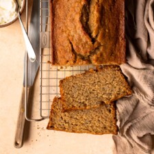 Banana bread with two slices cut on a wire cooling rack.
