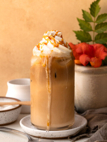 An iced caramel latte topped with whipped cream and a caramel drizzle.