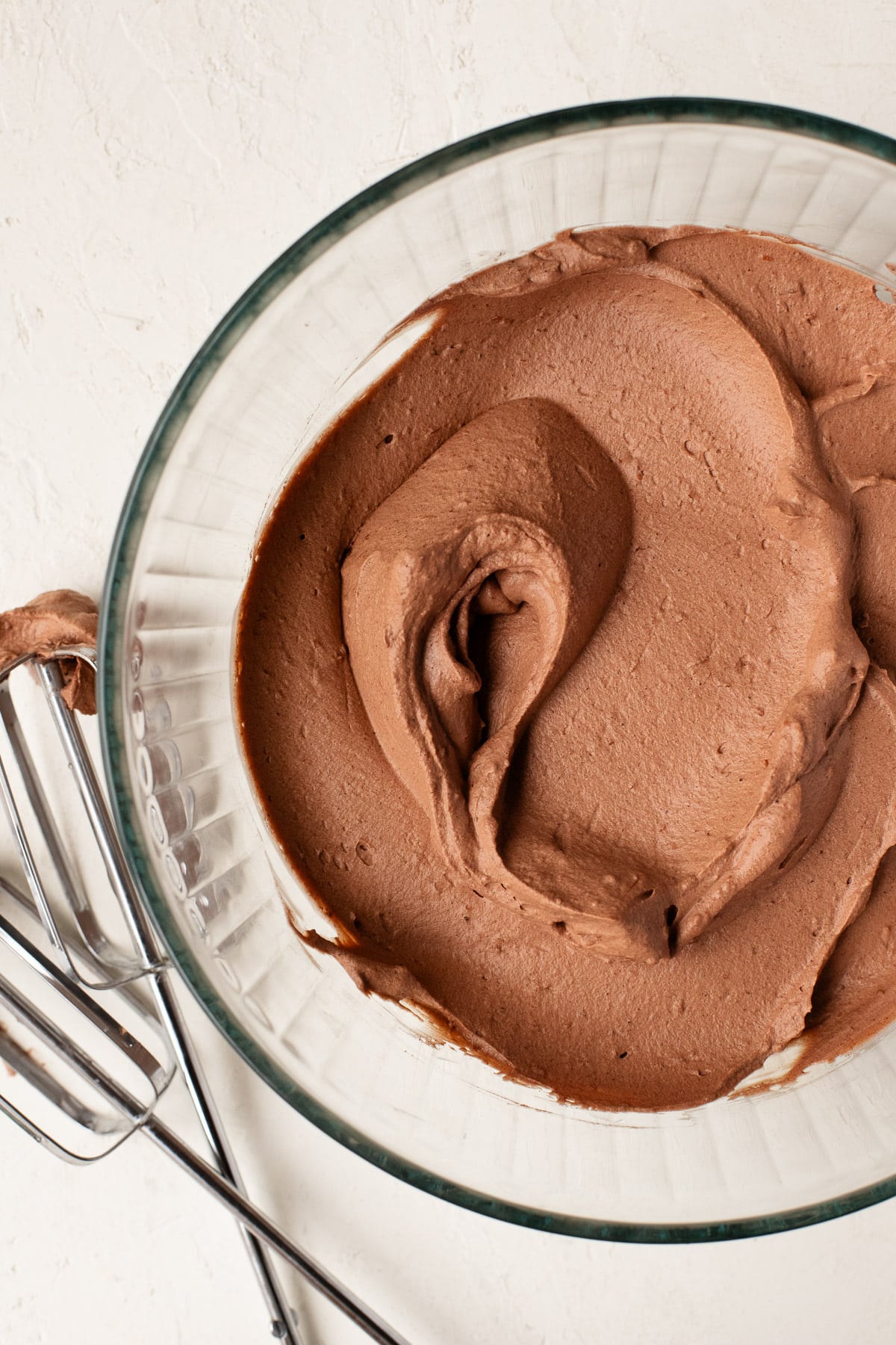 Chocolate cream whipped to stiff peaks in a large glass bowl.