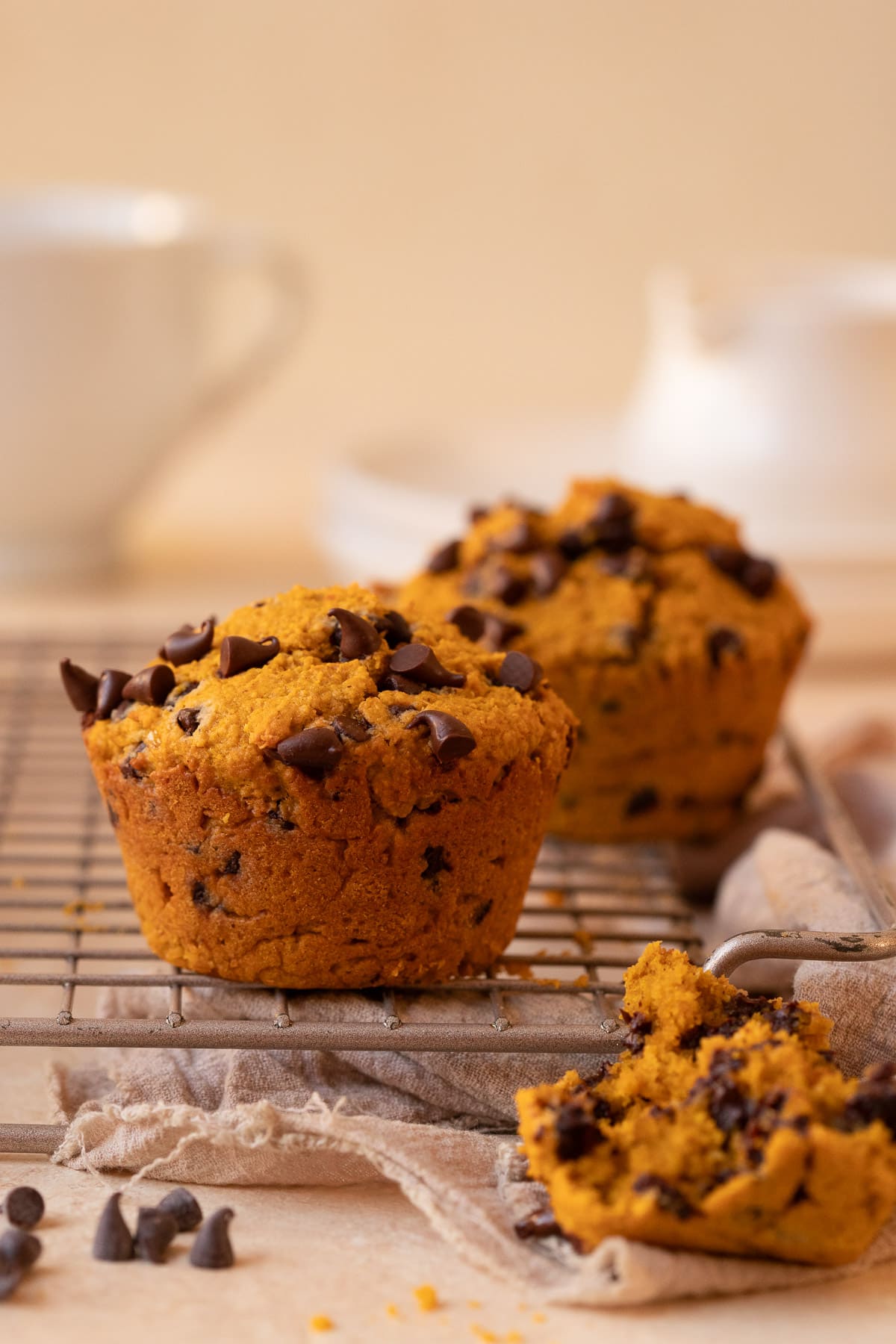 Two muffins on a wire cooling rack, with a portion of a third muffin in the foreground showing the crumb.