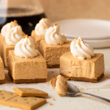 Mini cheesecake bars topped with whipped cream and served with coffee.