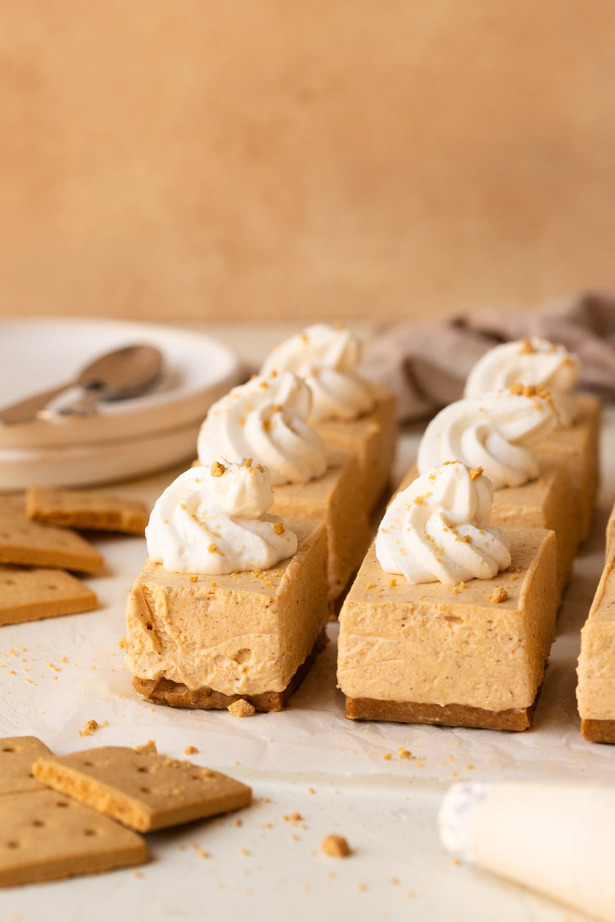 Pumpkin cheesecake bars sliced and topped with piped dollops of whipped cream.