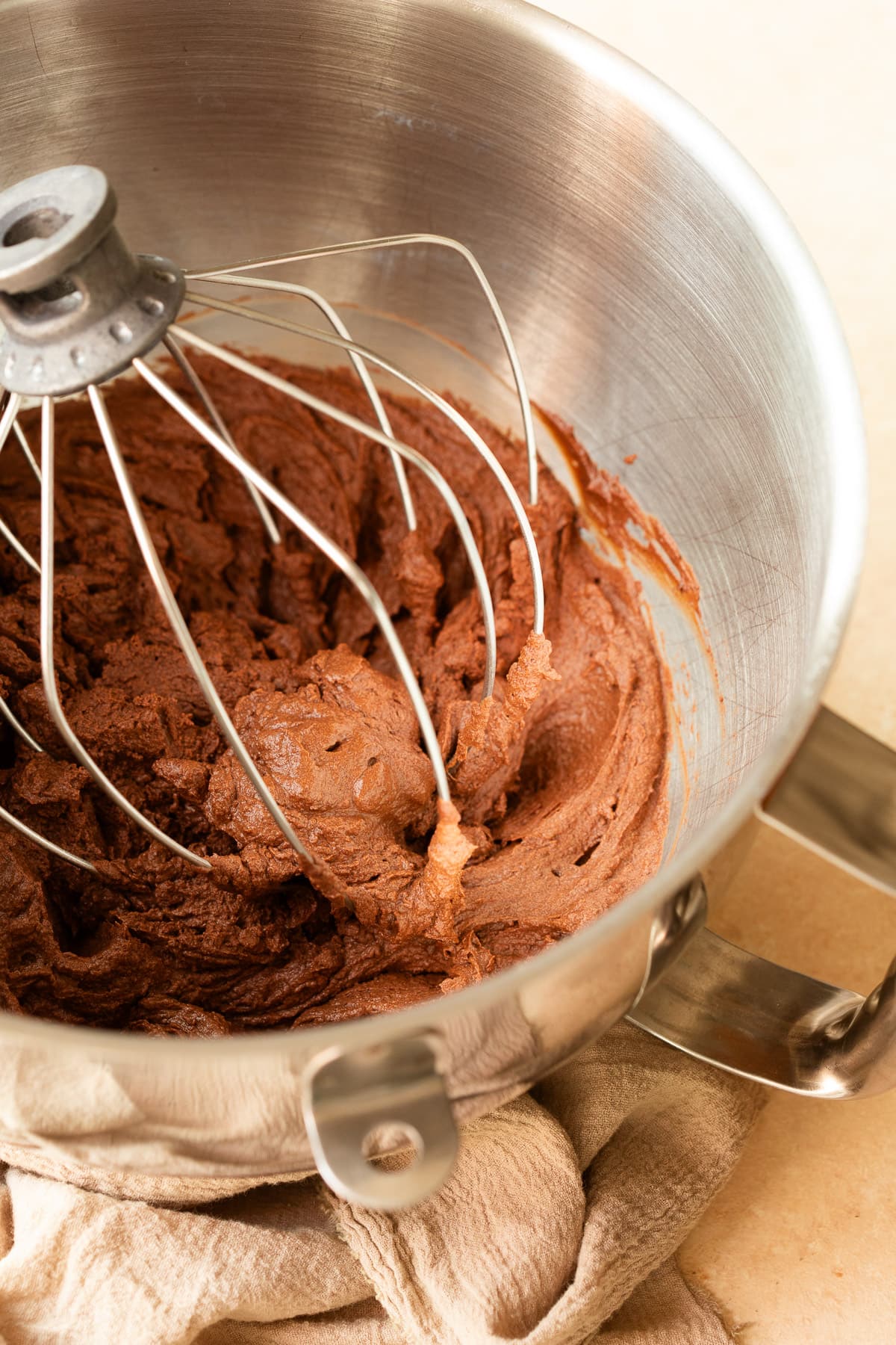 Chocolate ganache being whipped in a stand mixer with a wire whip.