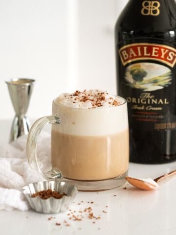 A Baileys latte made in a clear mug, topped with chocolate shavings.