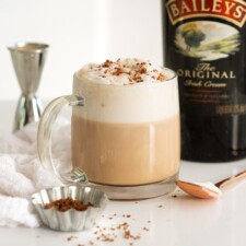 A Baileys latte made in a clear mug, topped with chocolate shavings.