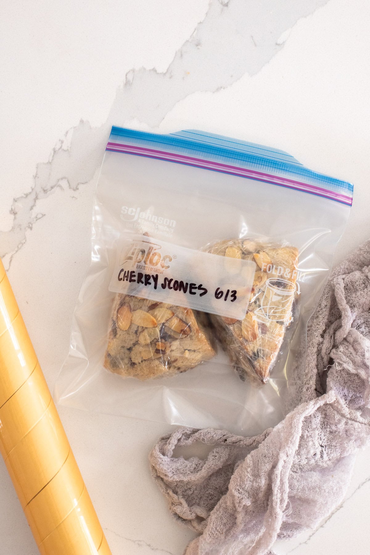 Baked scones wrapped in plastic wrap and stored in a freezer bag.