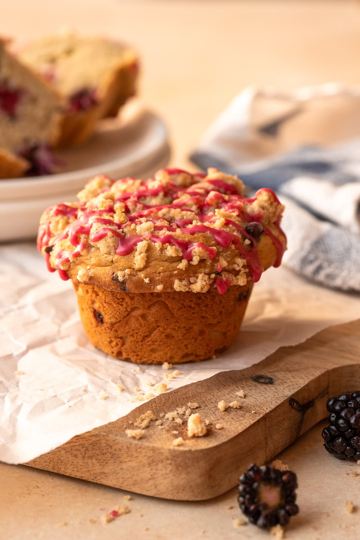 A muffin on parchment sitting atop a wooden board.