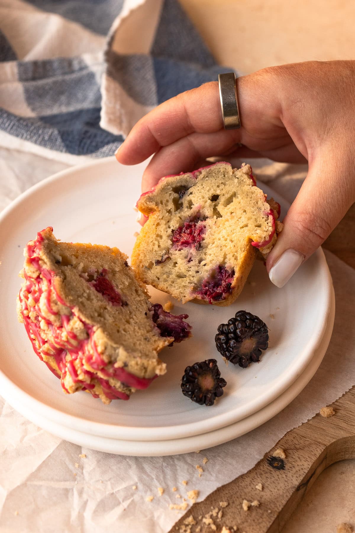 Two halves of a muffin on stacked plates with one half being lightly pressed between two fingers to show bounce and texture.