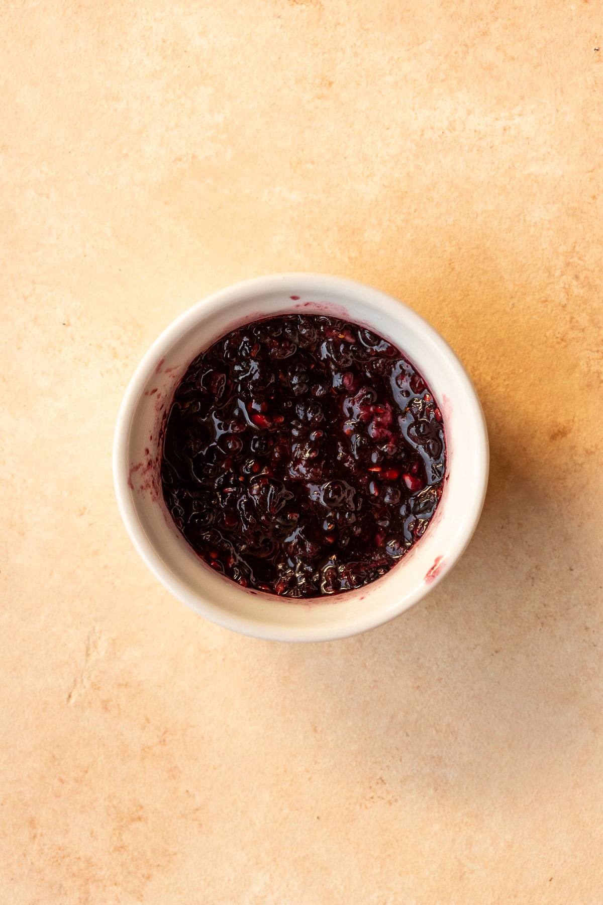 Mashed blackberries in a small white bowl.