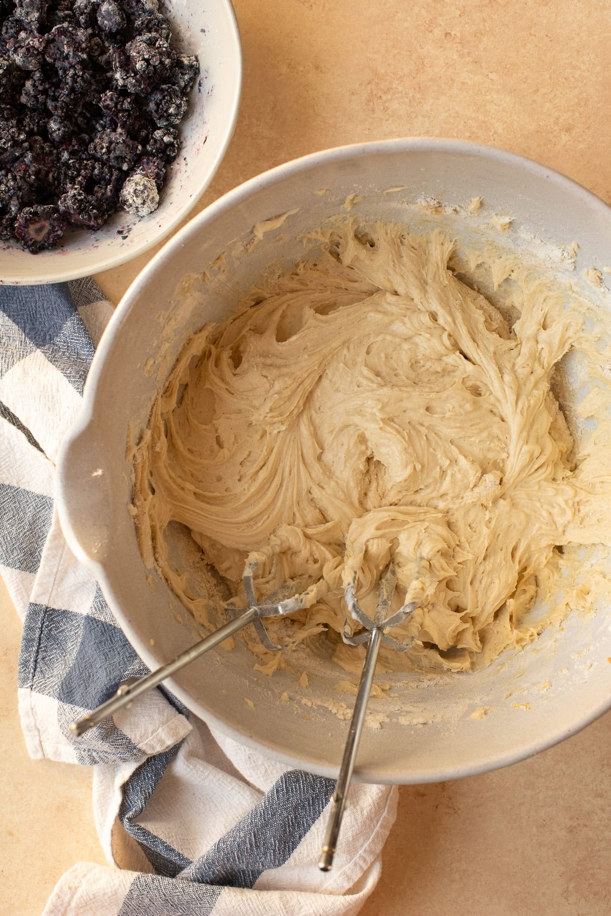 Muffin batter mixed together in a bowl with the beaters of a handheld mixer.