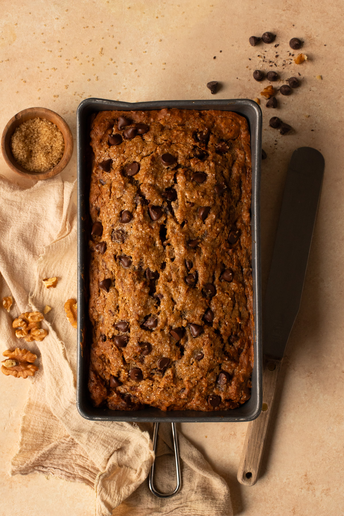 A loaf of chocolate chip banana nut bread in a baking pan.