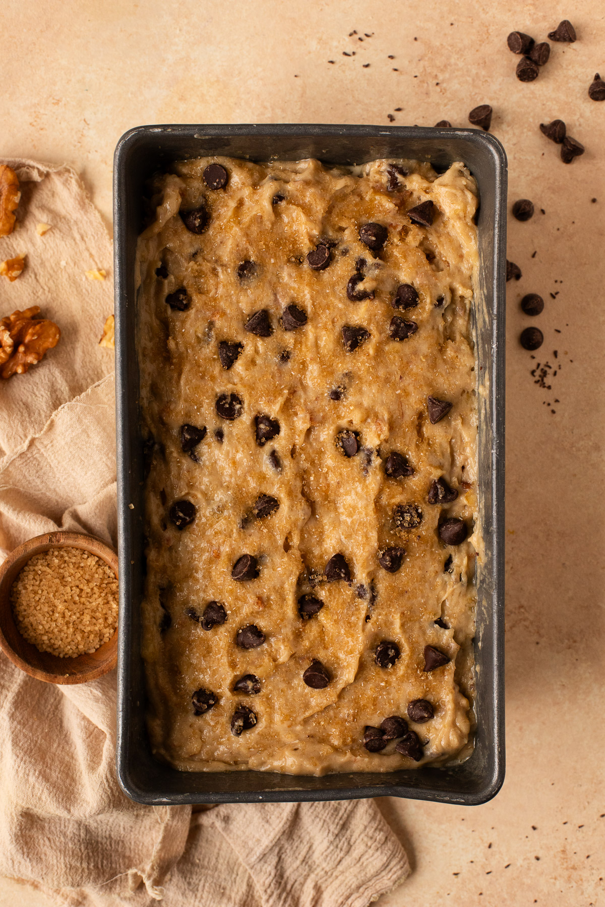 Banana bread batter in a loaf pan, topped with chocolate chips.